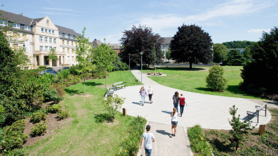 Wiesenumsäumter Platz vor einem großen Traditionsgebäude