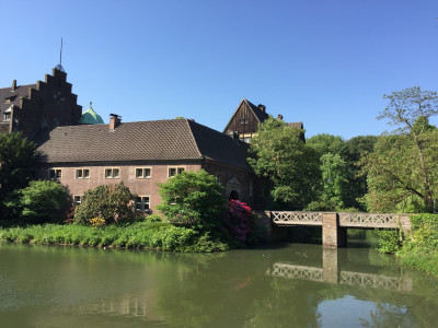 Burggraben, Gebäude und Fußgängerbrücke eines Wasserschlosses